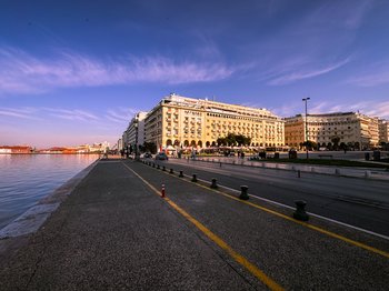 Панорамный вид на Площадь Аристотеля и набережную Салоник, демонстрирующий неоклассическую архитектуру и оживленную городскую жизнь у моря.